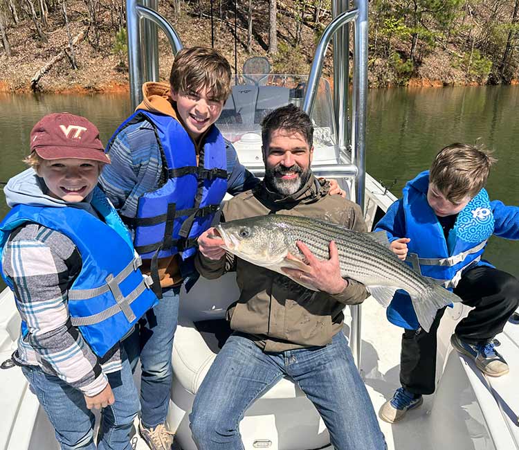 Family shows off lake fishing catch from boat.