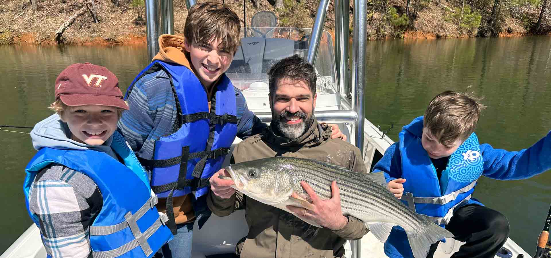 Family shows off lake fishing catch from boat.