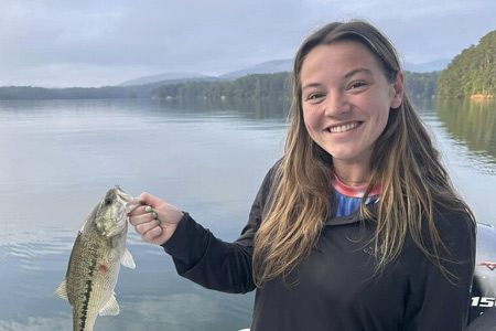  Woman holds up fish caught on lake fishing trip
