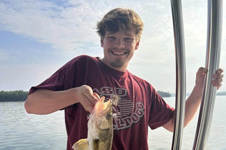  Man holds up lake fishing catch.