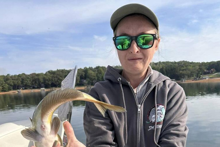  Another view of woman holding up fish caught on lake.
